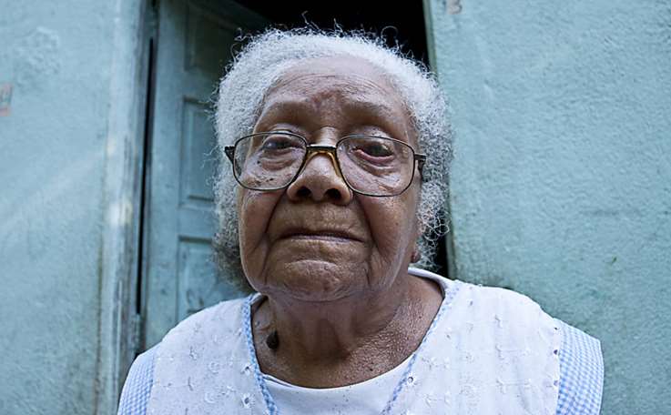 Maria de Souza de Oliveira, 84 anos, pousa para retrato na frente da sua casa. Dona Maria, como é conhecida, é uma das moradoras mais antigas da comunidade quilombola, localizada dentro da área da base naval de Aratu, no bairro de São Tomé de Paripe, limite da cidade de Simões Filho, a 21 km de Salvador