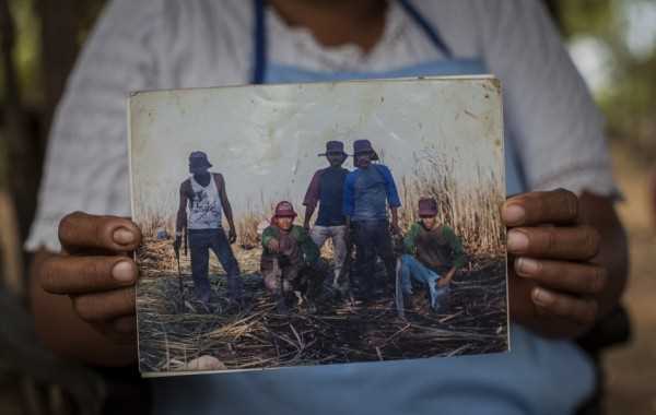 Uma mulher segura uma foto de seu marido com colegas de trabalho do canavial perto de Chichigalpa, Nicarágua. Ele morreu de doença crônica renal; quatro de seus filhos também tem a doença. / Anna Barry-Jester (Center for Public Integrity)