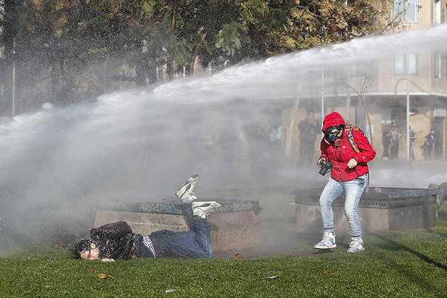Fotógrafo é atingido por jato d'água lançado por polícia para reprimir movimento grevista, em Santiago