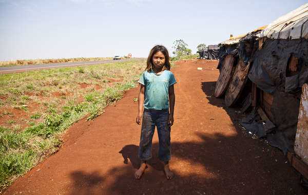 Niña guaraní de nueve años en el precario campamento de su comunidad al borde de la carretera. La más joven de las víctimas de suicidio tenía esta misma edad. © Paul Patrick Borhaug
