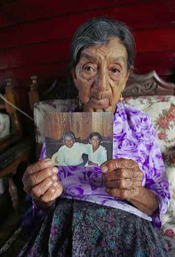 Viúva do petróleo, Maria Machay segura foto de seu saudoso marido, um dos vários acometidos por câncer em sua localidade.